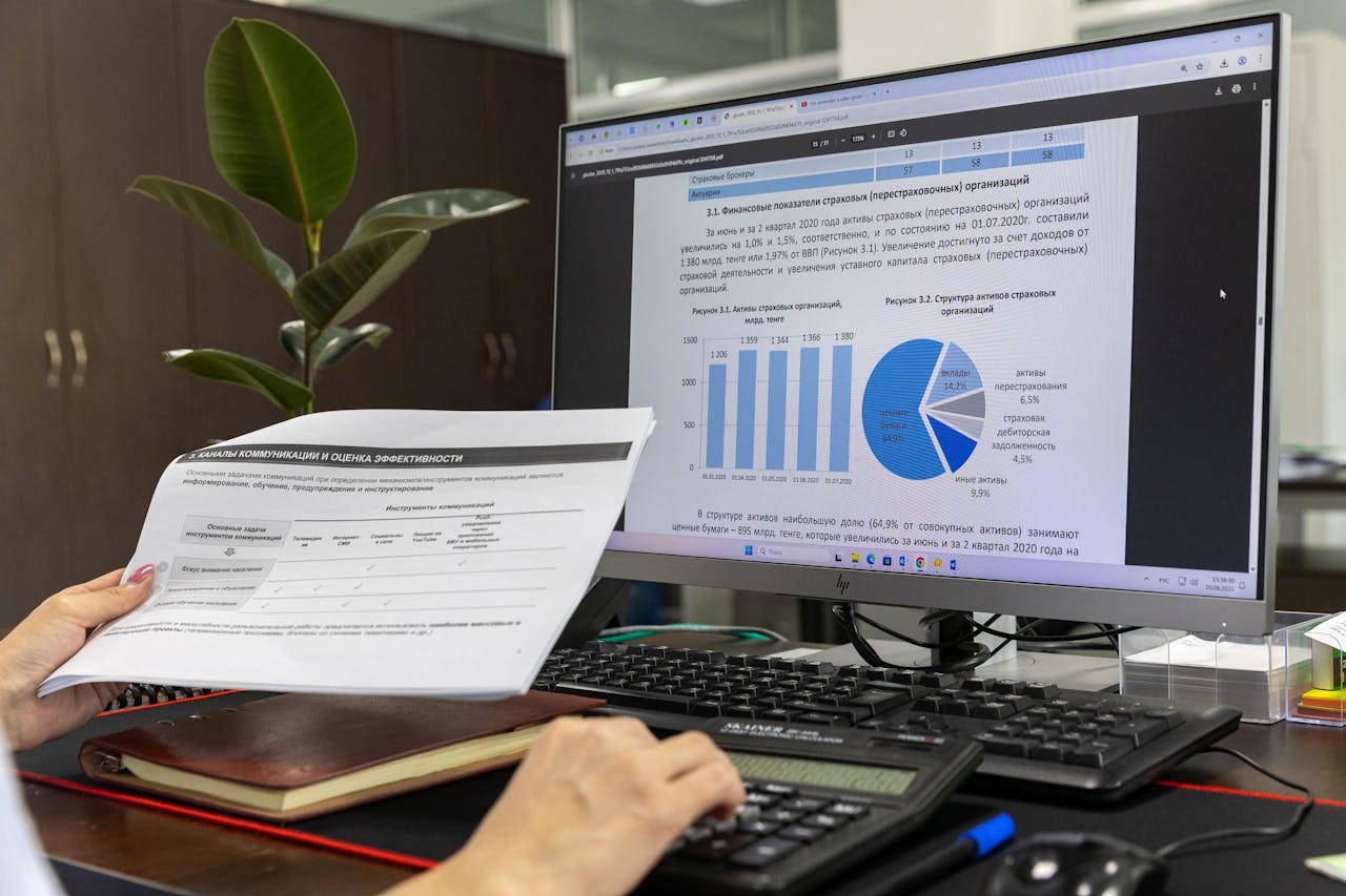 About Person analyzing financial data on a computer screen in an office setting.
