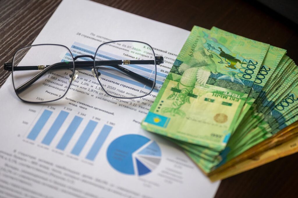 Profit Backup me ayudó a evitar una pérdida segura Kazakhstani tenge notes and financial reports on a desk, depicting financial analysis.